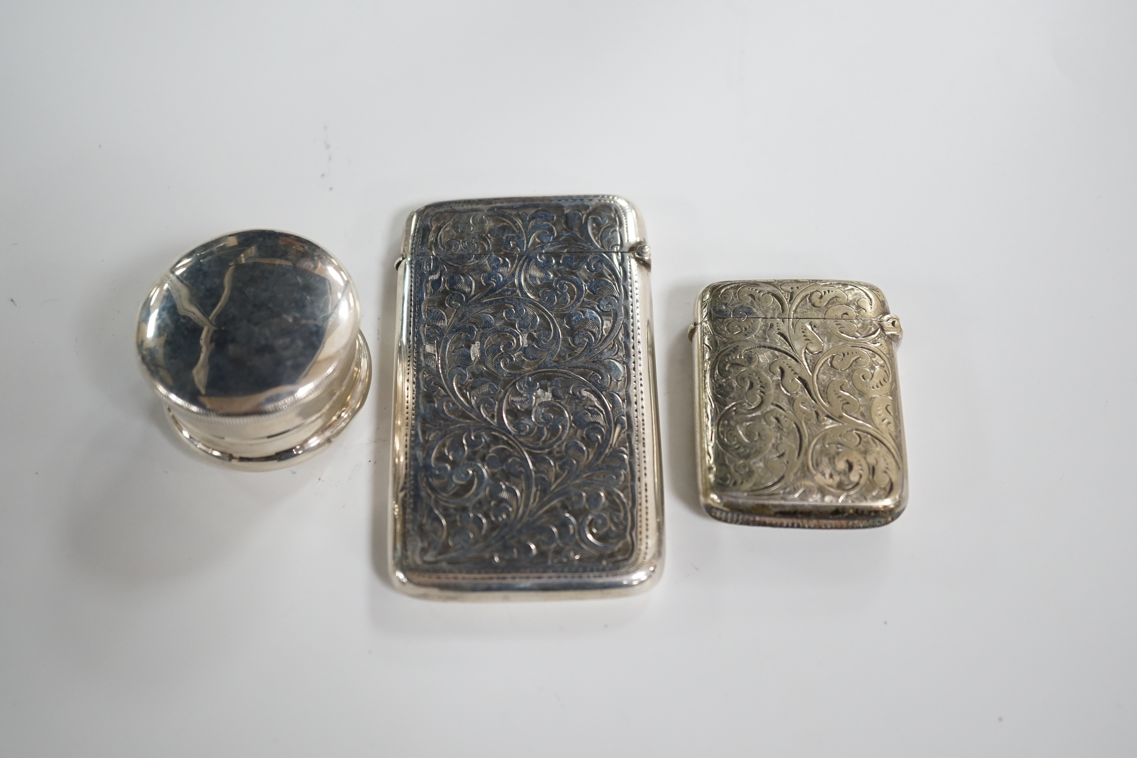 An Edwardian engraved silver card case, Birmingham, 1906, 84mm, together with a silver plated vesta case and a silver pill box. Condition - card and vesta cases, fair, pill box mis-shapen